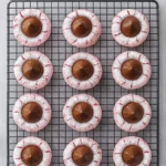 Pink blossom cookies topped with chocolate kisses and powdered sugar on cooling rack.