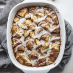 Top-down view of cinnamon apple bake with cream cheese glaze in a white casserole dish.