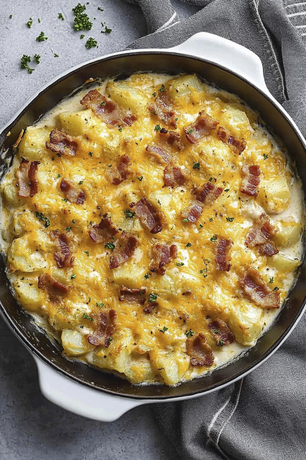 Cheesy potato casserole baked in a white skillet with crispy bacon and melted cheddar cheese.