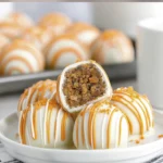 White chocolate carrot cake truffles with orange drizzle and carrot decoration on a dessert plate.