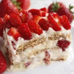 Strawberry icebox cake slice with layers of cream, graham crackers, and fresh strawberries on top