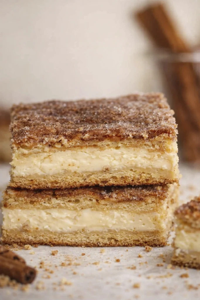 Stacked vanilla custard dessert bars with soft cake layers and cinnamon sugar topping