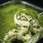 Close-up of matcha tiramisu with spoon lifting a creamy bite showing layered texture and green tea powder