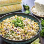 Creamy Mexican street corn salad with cheese, jalapeños, cilantro, and lime served in a rustic bowl.