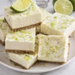 Creamy no-bake key lime cheesecake bars with graham cracker crust and fresh lime zest on a white plate.