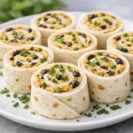 Creamy tortilla pinwheel wraps filled with cheese spread and herbs, sliced into bite-sized appetizers and arranged on a white plate.