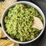Chunky homemade guacamole in a white bowl served with crispy tortilla chips