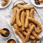 Crispy cinnamon sugar churros served with chocolate and caramel dipping sauces in a rustic tray.