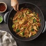 Freshly cooked noodles tossed with chicken and vegetables in a hot wok