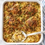 Overhead view of creamy baked chicken and rice casserole with crispy fried onions, melted cheese, and fresh parsley in a white baking dish.