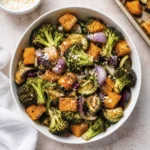 White bowl filled with roasted broccoli, butternut squash, zucchini, mushrooms, red onions, and Parmesan cheese served as a healthy vegetable side dish.