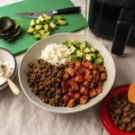 Bowl with roasted sweet potatoes, seasoned ground beef, cottage cheese, avocado, and a drizzle of hot honey