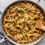 Creamy Cajun chicken penne pasta with green onions in a skillet.
